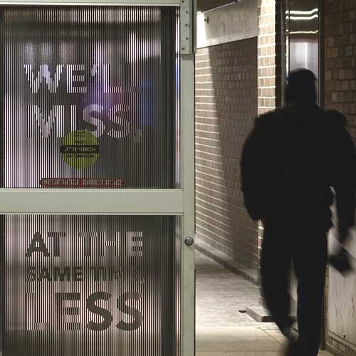A man walks in a hallway and passes two sliding doors with a text stuck on them.